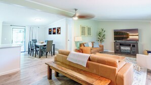 Een woonkamer met een bank, een salontafel, een eethoek met stoelen en een open haard.
