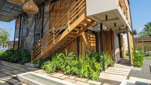 A modern building with a wooden staircase, a covered outdoor area, and a variety of plants.
