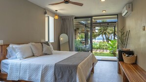 A bedroom with a bed, a ceiling fan, a large window, and a view of the outdoors.