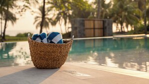 A wicker basket with towels by a poolside.