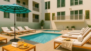Ein Poolbereich mit Liegestühlen, einem Tisch mit Getränken und einem blauen Sonnenschirm.