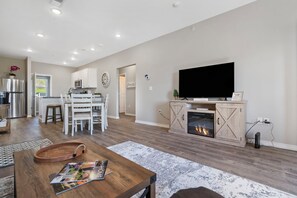 Una sala de estar moderna con chimenea, un televisor de pantalla plana y un comedor con mobiliario blanco.