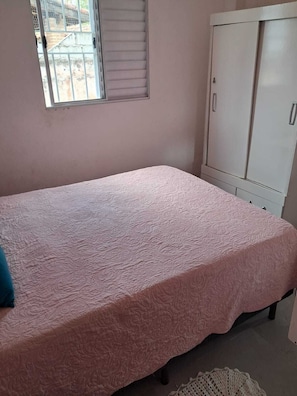 Een slaapkamer met een bed, een kledingkast en een raam.