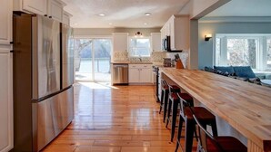 Une cuisine moderne dotée d’appareils électroménagers en acier inoxydable, d’un comptoir-bar en bois et offrant une vue sur l’extérieur.