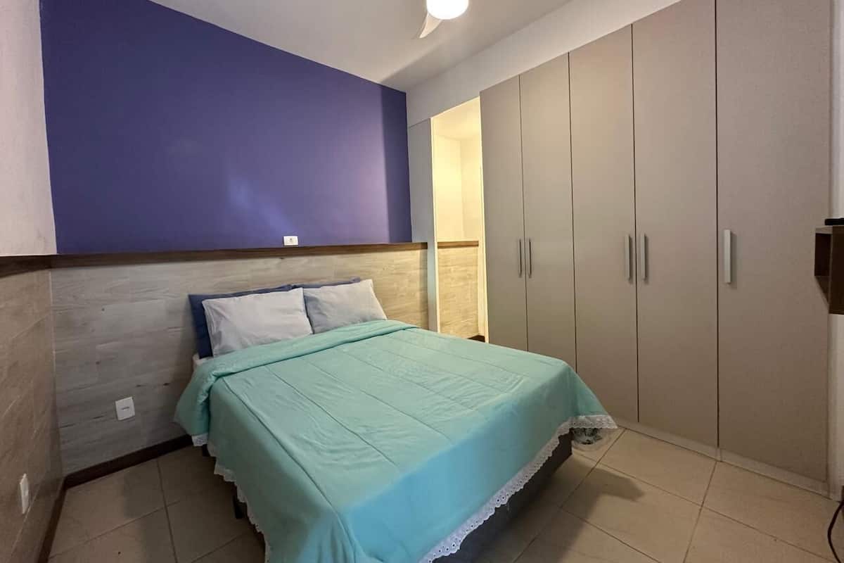 A bedroom with a bed, a wardrobe, and a ceiling fan.