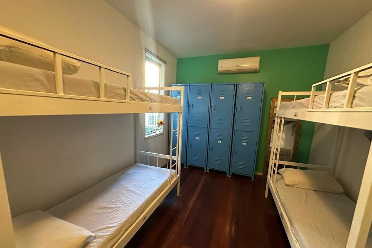 A dormitory room with bunk beds, a window, and a row of lockers.