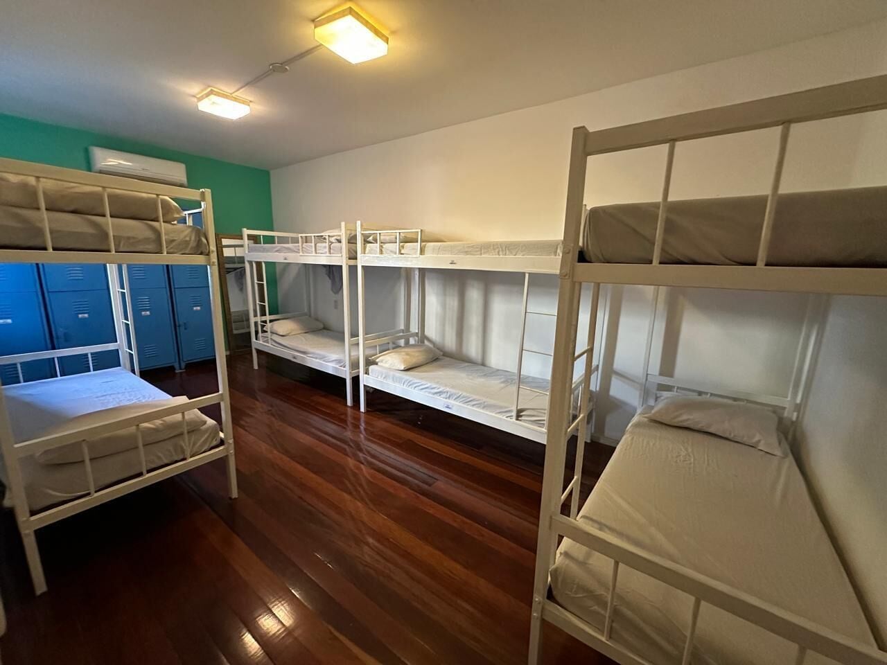 Un dormitorio con literas, suelo de madera y taquillas azules.