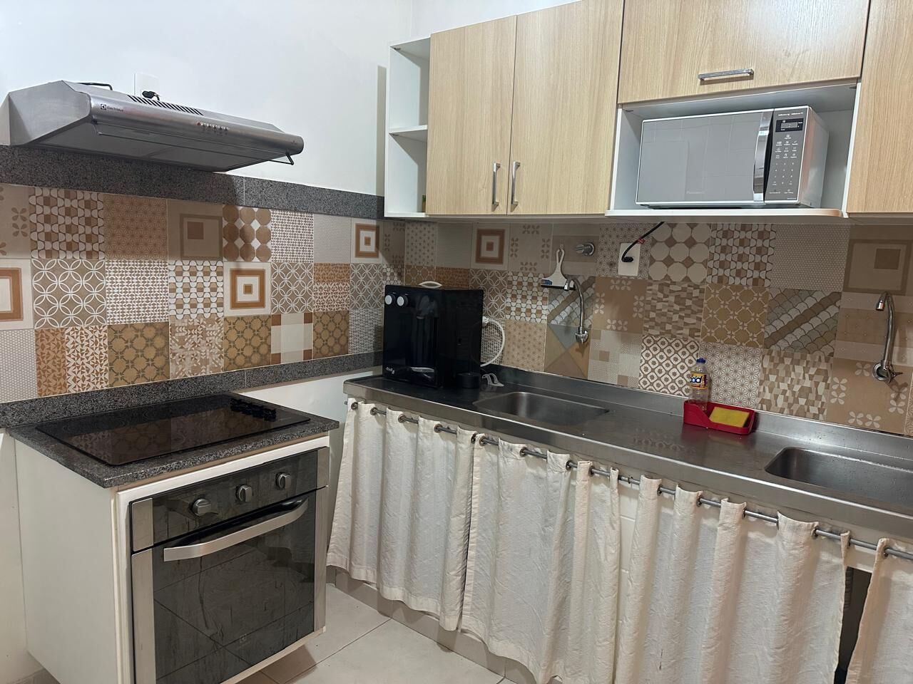 A compact kitchen with a stove, oven, microwave, and a coffee maker.