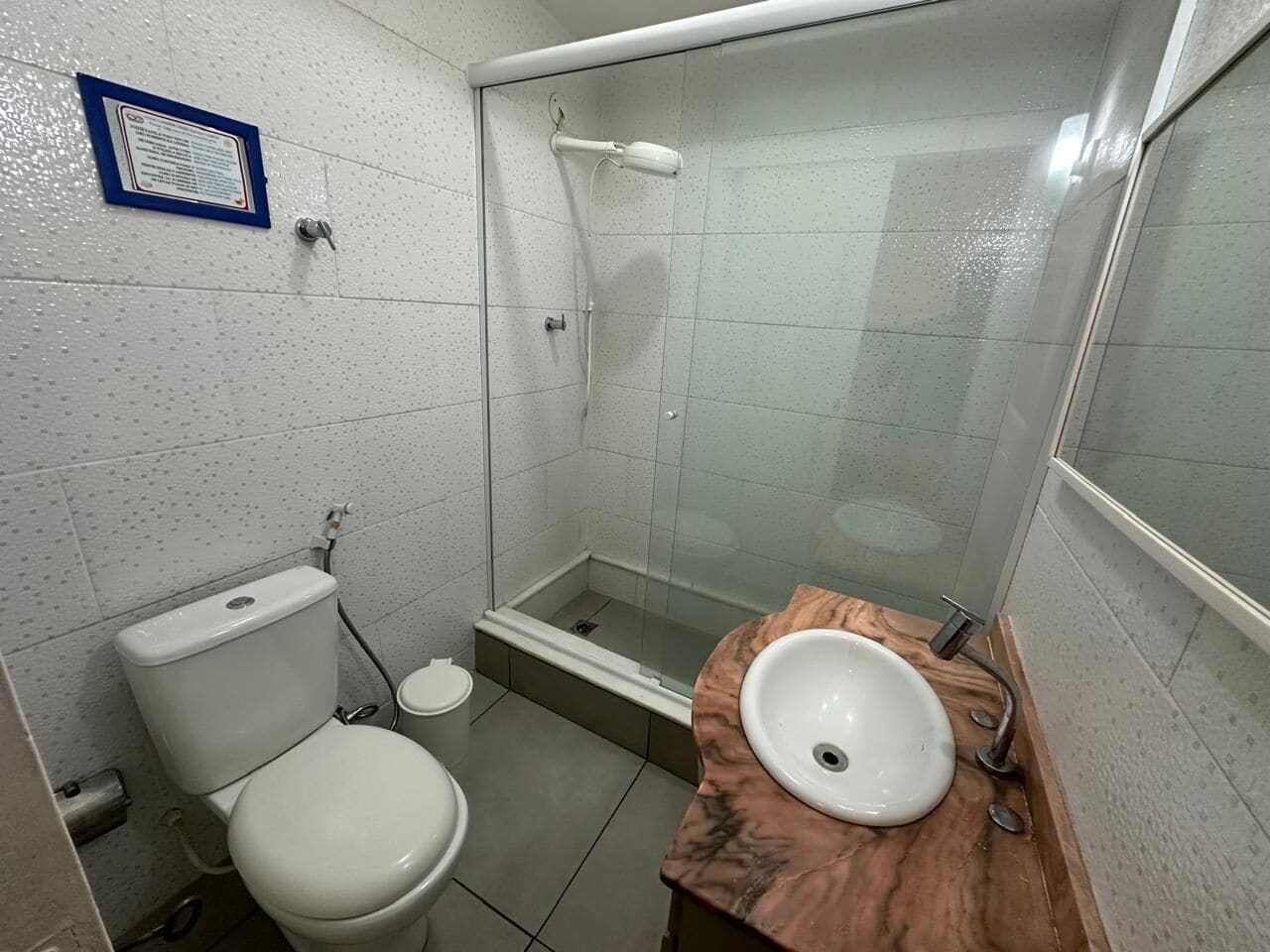 A small bathroom with a toilet, a sink, and a glass-enclosed shower.
