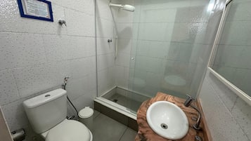 A small bathroom with a toilet, a sink, and a glass-enclosed shower.