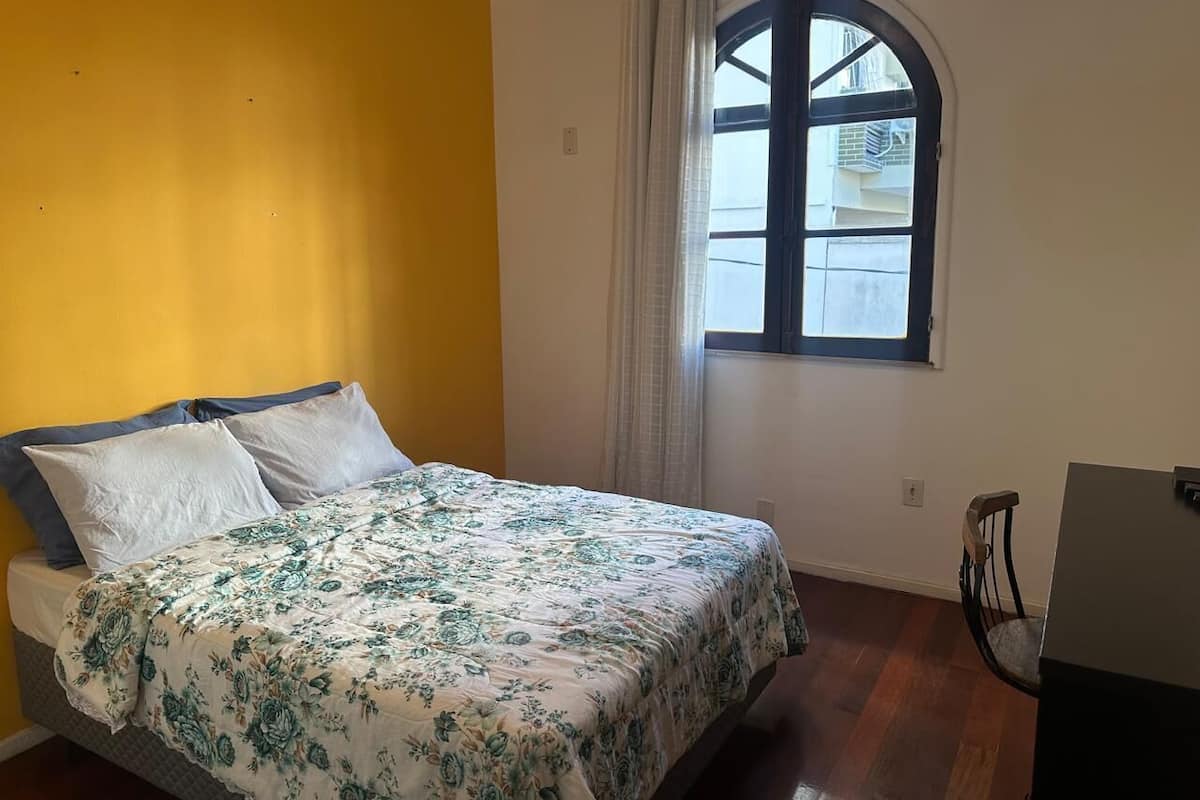 A bedroom with a bed, a chair, a window, and a door.