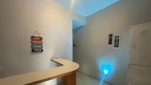 Zona de recepción con mostrador curvo, un cartel en la pared y una luz azul en el suelo.