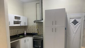 A kitchen with white cabinets, a stove, and a refrigerator. - Apartment in the heart of Oran, near the seafront (Oran)