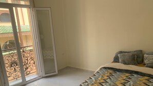 A bedroom with a bed, a balcony with a decorative railing, and a sliding glass door. - Apartment in the heart of Oran, near the seafront (Oran)
