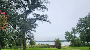 A wooden deck with a view of a grassy area and a lake.