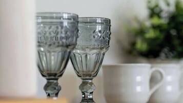 Two clear glass cups on a wooden surface with a white mug in the background.