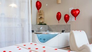 A spa room with a bathtub, a white chair, and red heart-shaped balloons on the wall. - Sensual suite and balneotherapy (Nemours)