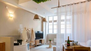 A modern living room with a TV, wooden furniture, a dining table set, and large windows. - Sensual suite and balneotherapy (Nemours)