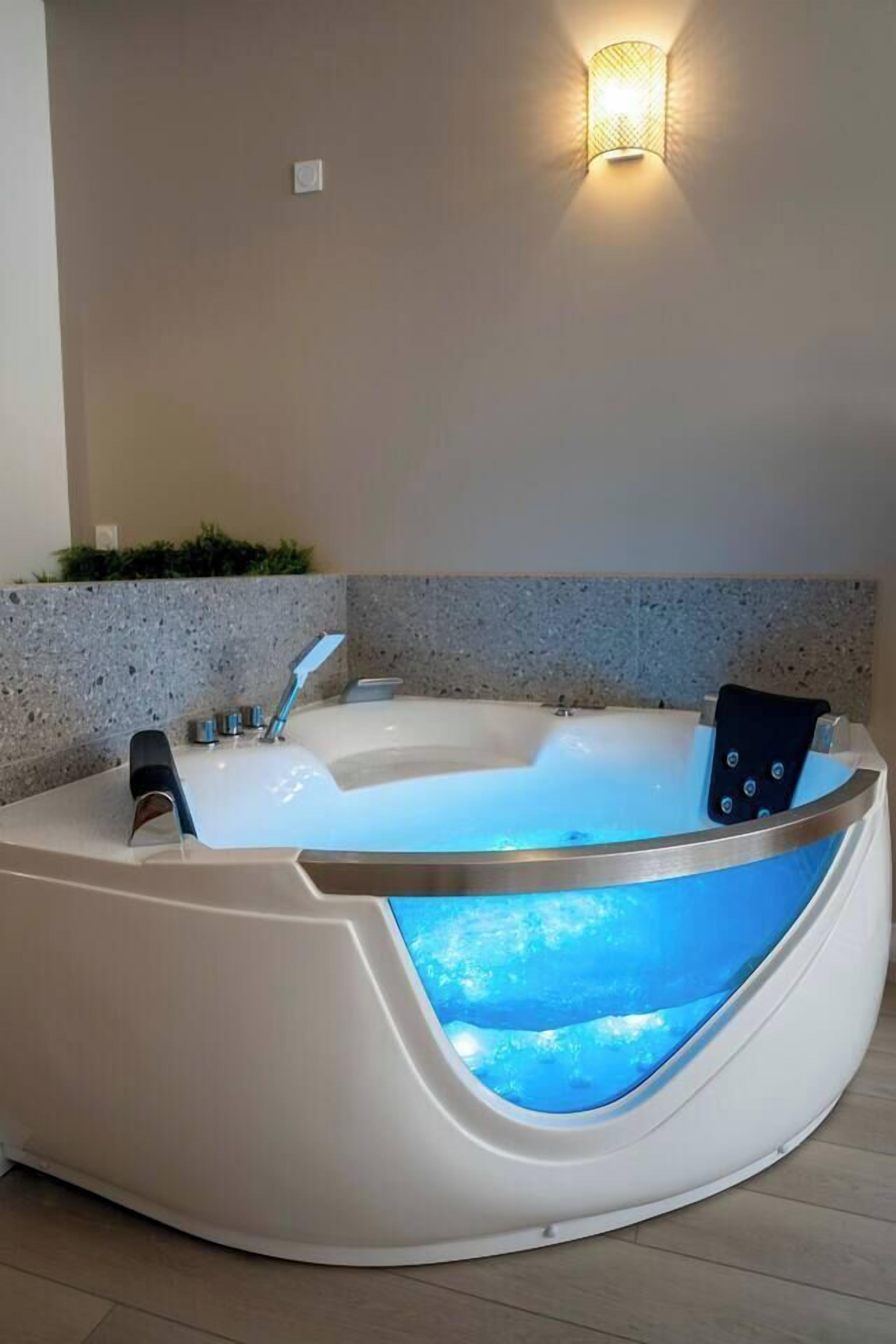 A modern spa tub with a built-in water feature, a wall-mounted light fixture, and a granite countertop.