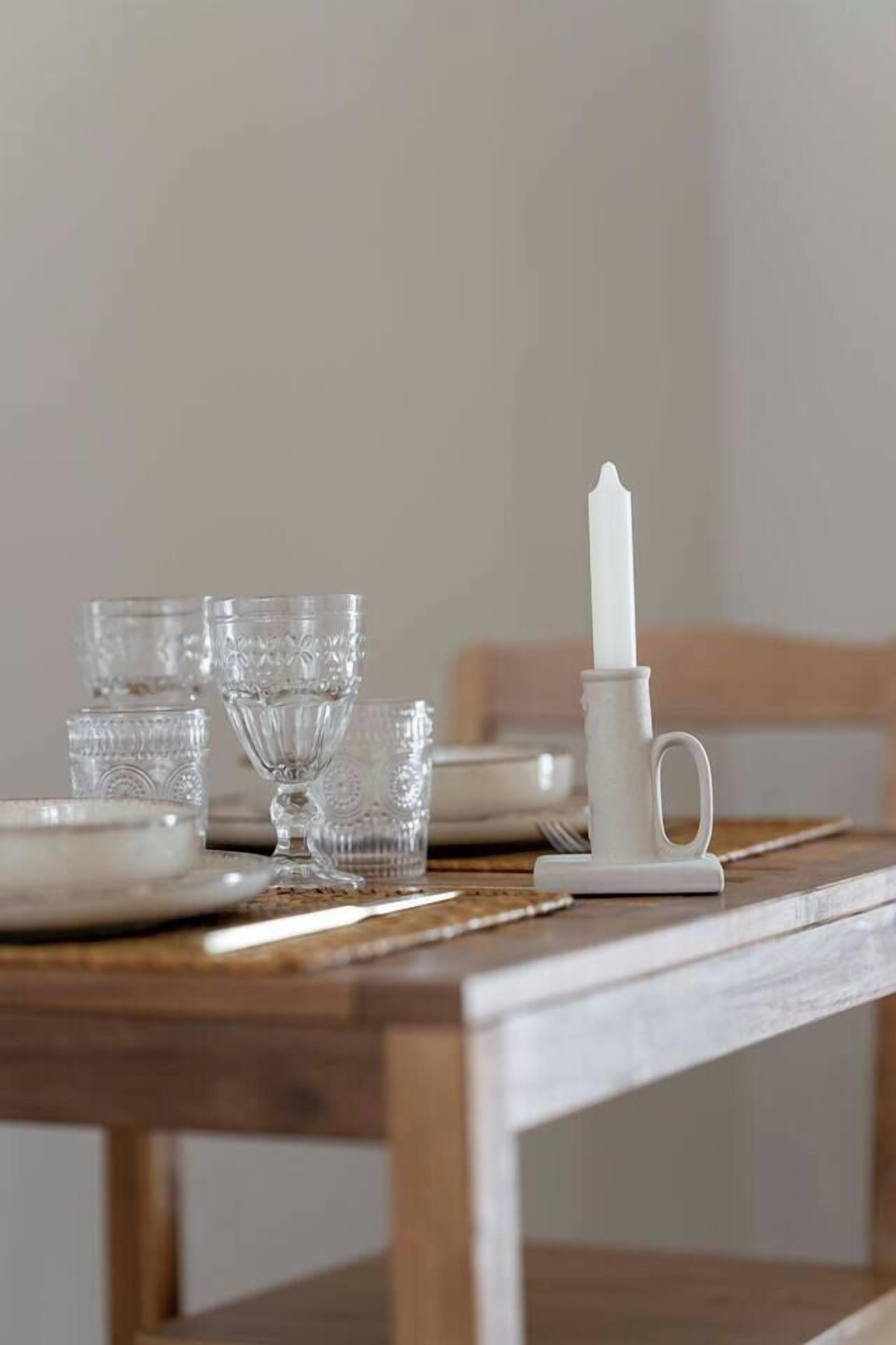 Une table à manger avec de la vaisselle en verre transparent et un chandelier blanc.