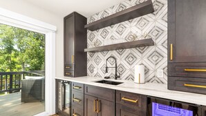 A modern kitchen with dark cabinetry, a white countertop, and a patterned backsplash. - Lakefront 4BR, Hot Tub, Kayaks, Paddleboards, Fire pit, Fireplace, Pool Table (Littleton)