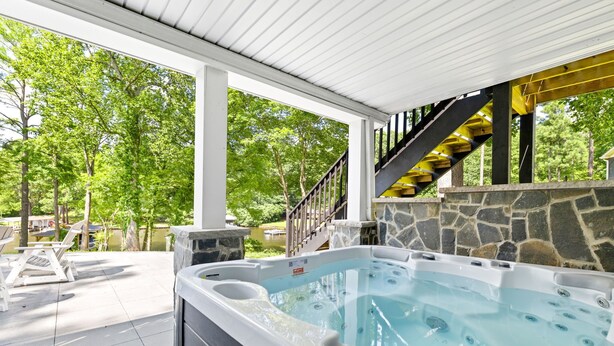 A hot tub with a stone wall and a staircase leading to a covered area. - Lakefront 4BR, Hot Tub, Kayaks, Paddleboards, Fire pit, Fireplace, Pool Table (Littleton)