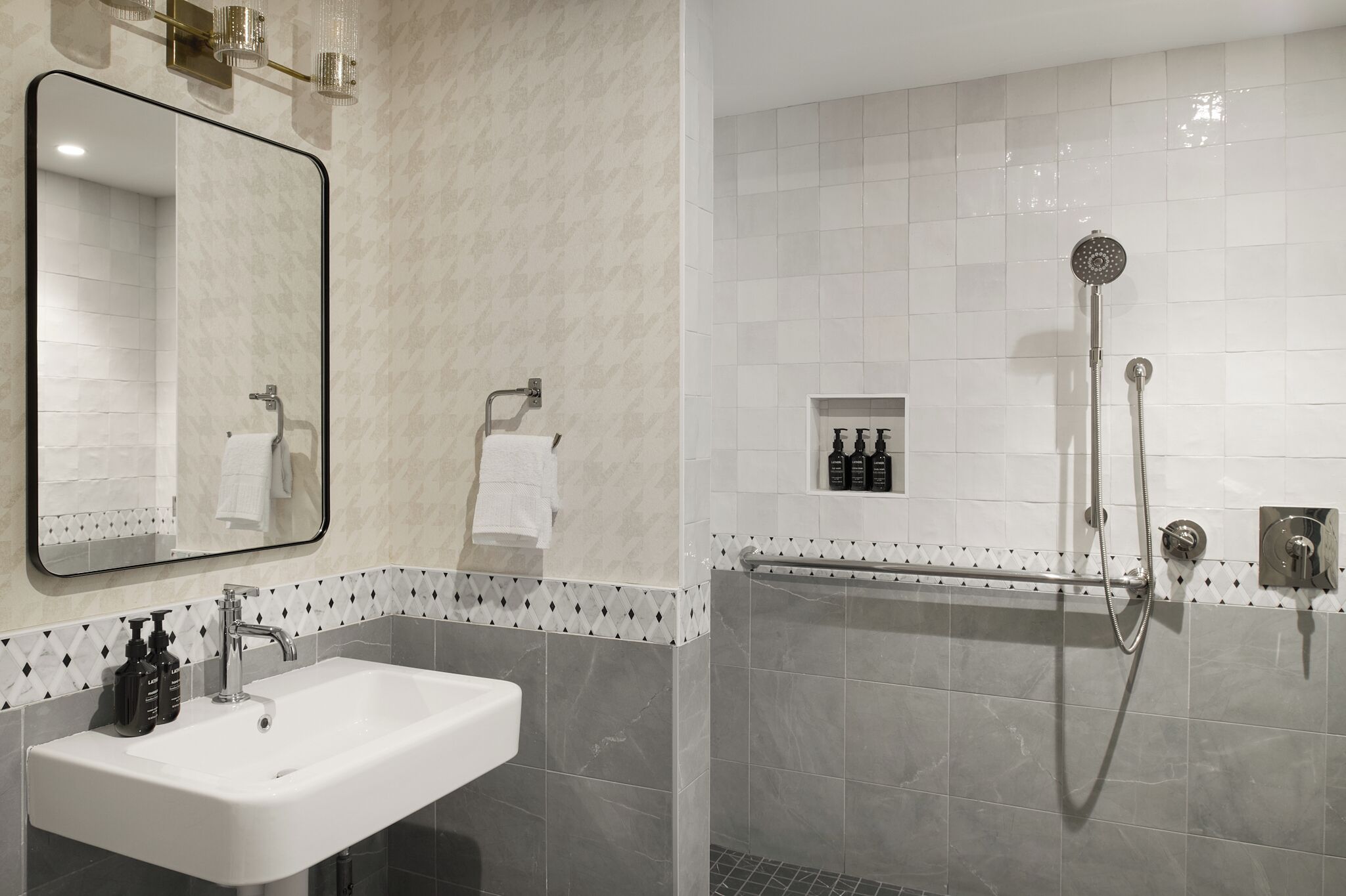 Un baño con lavamanos, espejo, ducha y artículos de aseo.