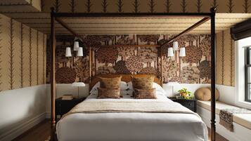 Ein Himmelsbett mit gemustertem Wandpapier, Nachttische und ein Fenster mit Blick.