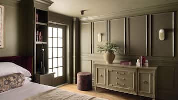 Une chambre à coucher comprenant un lit, une table de chevet, une commode, une fenêtre et une bibliothèque.