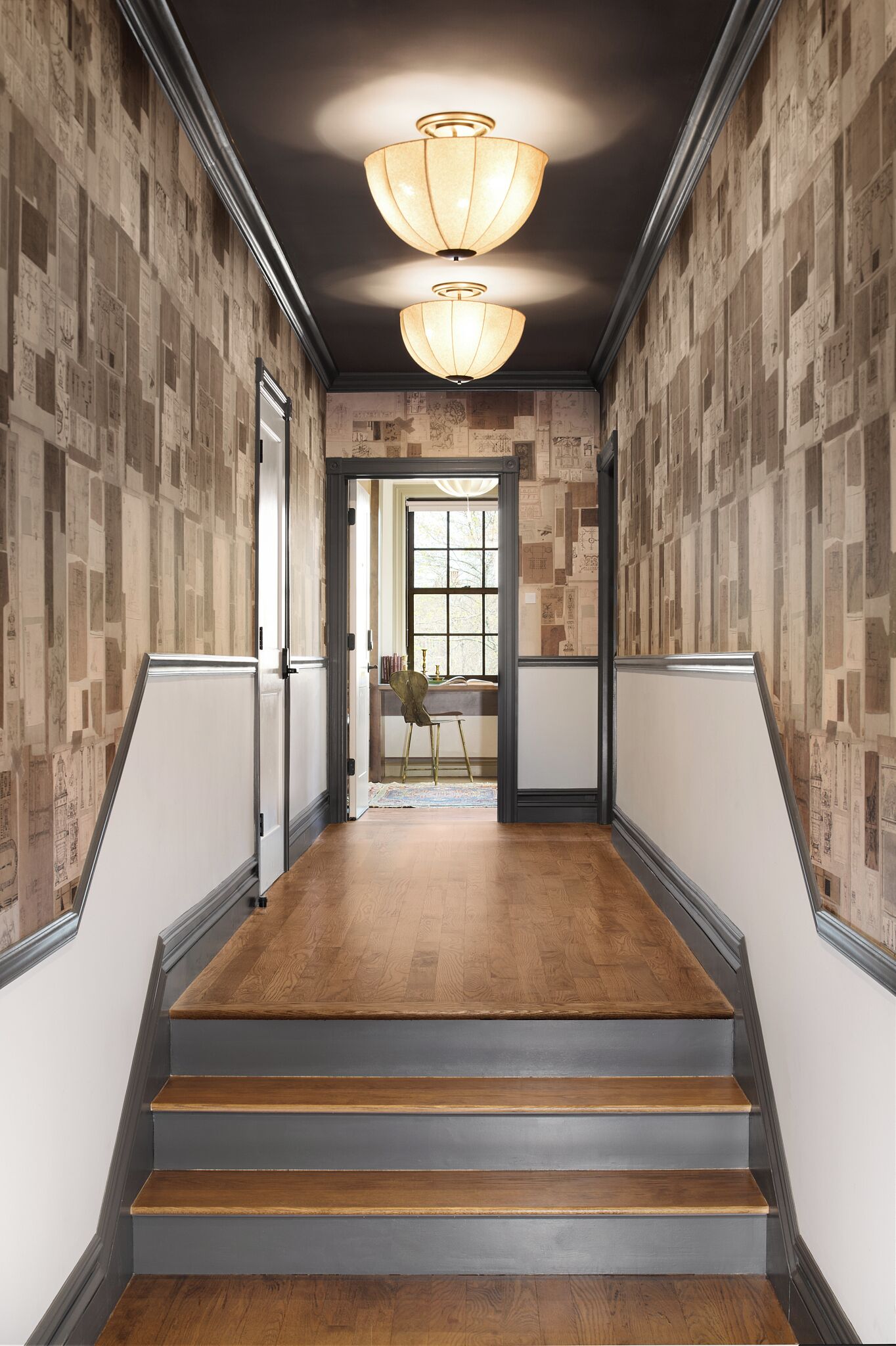 Una escalera con escalones de madera y un techo oscuro, que lleva a una habitación con una ventana y una silla.