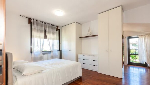 A bedroom with a bed, a wardrobe, a dresser, and a window with curtains.
