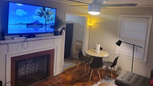 Un soggiorno con televisore, camino, ventilatore a soffitto, tavolo da pranzo e sedie.