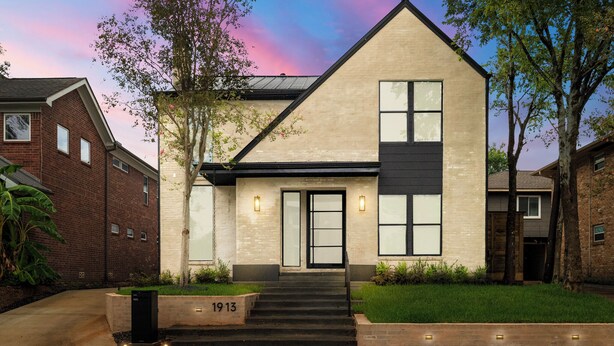 A modern two-story house with a brick facade, a large front door, and a number '1913' on the front steps.