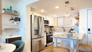 Una cocina moderna con electrodomésticos de acero inoxidable, una isla central y taburetes de mimbre.