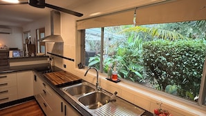 Una cocina moderna con un ventanal grande, armarios de madera, un lavamanos y un frutero sobre la encimera.