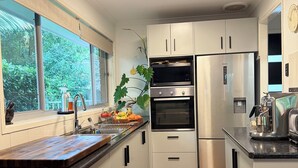 Una cocina moderna con armarios blancos, encimera de madera, horno empotrado, refrigerador y ventilador de techo.