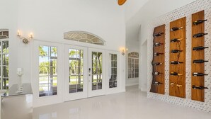 A spacious room with white walls, large glass doors leading to a garden, and a wine rack on the right wall. - Waterfront luxury estate. (Punta Gorda)