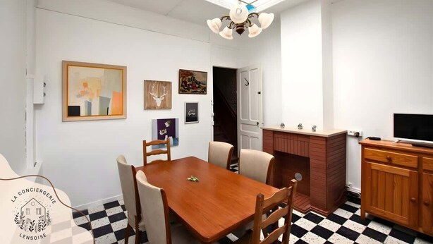 Un comedor con mesa y sillas de madera, una araña y obras de arte en las paredes.