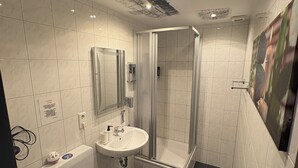 A modern bathroom with a toilet, sink, and glass-enclosed shower. - Restaurant Hotel Friesdorfer Hof (Bonn)