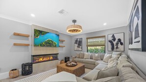 A modern living room with a fireplace, a large flat-screen TV, and a comfortable sofa.