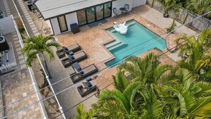 A rooftop pool with lounge chairs, a swan decoration, and surrounding palm trees.