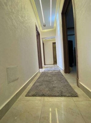 A hallway with a grey carpet and light-colored walls. - Alrehab and awesome (Cairo Governorate)