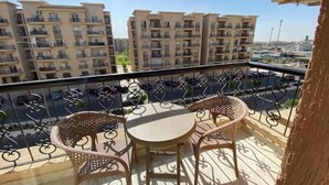 A balcony with a table and chairs, overlooking a residential area with multiple apartment buildings. - Alrehab and awesome (Cairo Governorate)