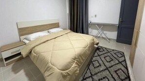 A bedroom with a bed, a nightstand, a wardrobe, an air conditioning unit, and a patterned rug. - Alrehab cozy apartment (Cairo Governorate)