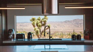 Une cuisine au design moderne, dotée d’une grande fenêtre et offrant une vue sur un paysage désertique.