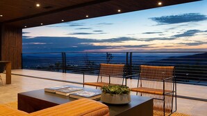 Un espace extérieur moderne, aménagé pour se détendre, avec vue sur l’océan au crépuscule.