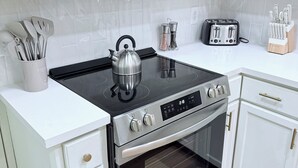 Et moderne køkken med hvide skabe, en rustfrit stål Bosch mikrobølgeovn, en sort induktionskogetop, en Frigidaire ovn og en brødrister.