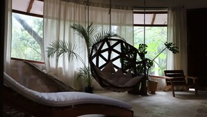 A room with a wooden lounge chair, a hanging chair, and several potted plants. - Tulum Jungle House with Swimming Pool - Relax and Spiritual Connection (Macario Gómez)