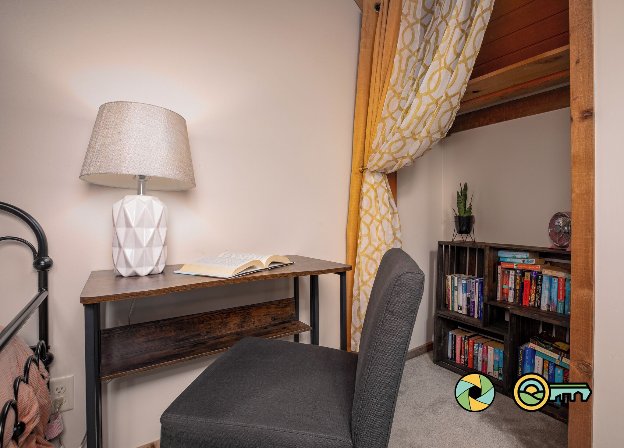 A study area with a desk, chair, lamp, open book, bookshelf, and a potted plant.