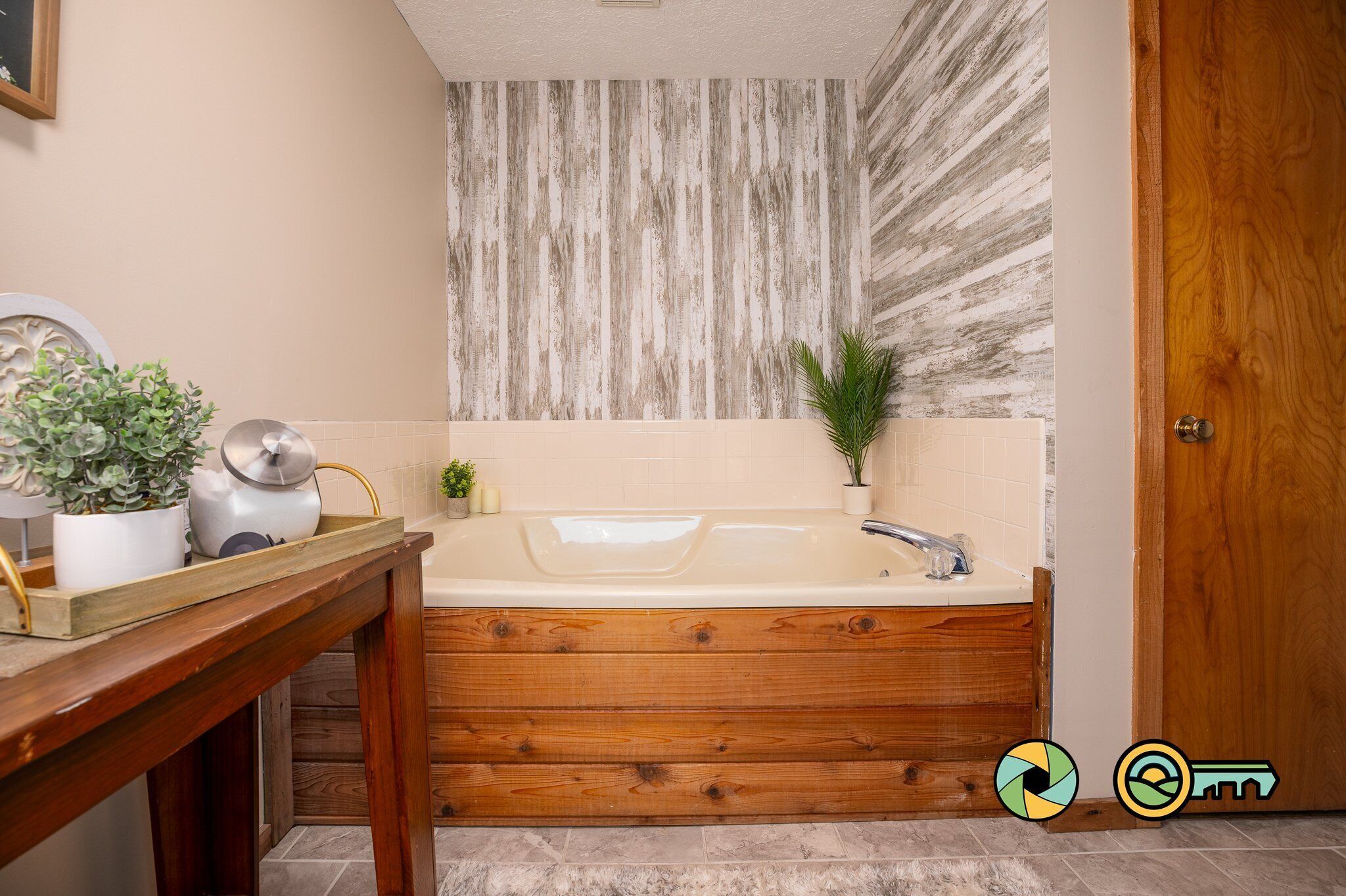 Une salle de bain avec une baignoire en bois, un lavabo et une plante en pot.